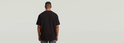 Modelo usando la camiseta GS-01 Relaxed de color negro, vista desde atrás, resaltando su corte relajado.