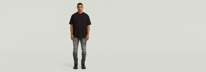Hombre usando la camiseta GS-01 Relaxed color negro con jeans rasgados en fondo claro.