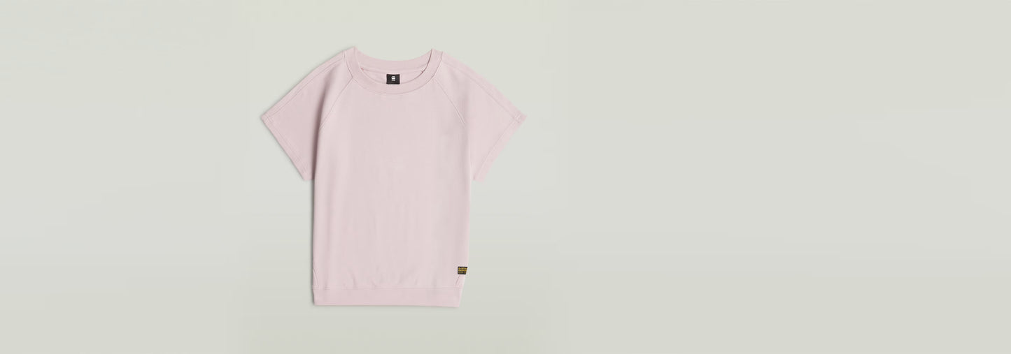 Camiseta Raglan de color rosa claro con mangas de casquillo y cuello redondo en 100 % algodón ecológico.