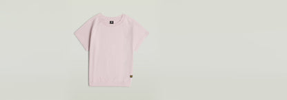 Camiseta Raglan de color rosa claro con mangas de casquillo y cuello redondo en 100 % algodón ecológico.