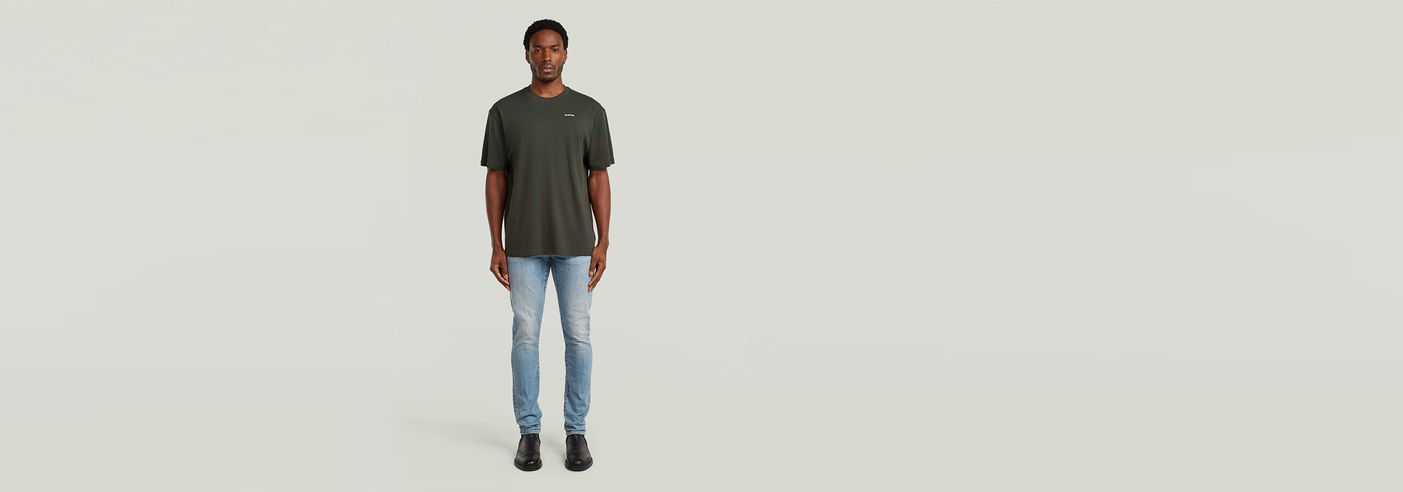 Modelo usando la Camiseta Rib Insert Relaxed en color verde, combinada con jeans claros, fondo neutro.