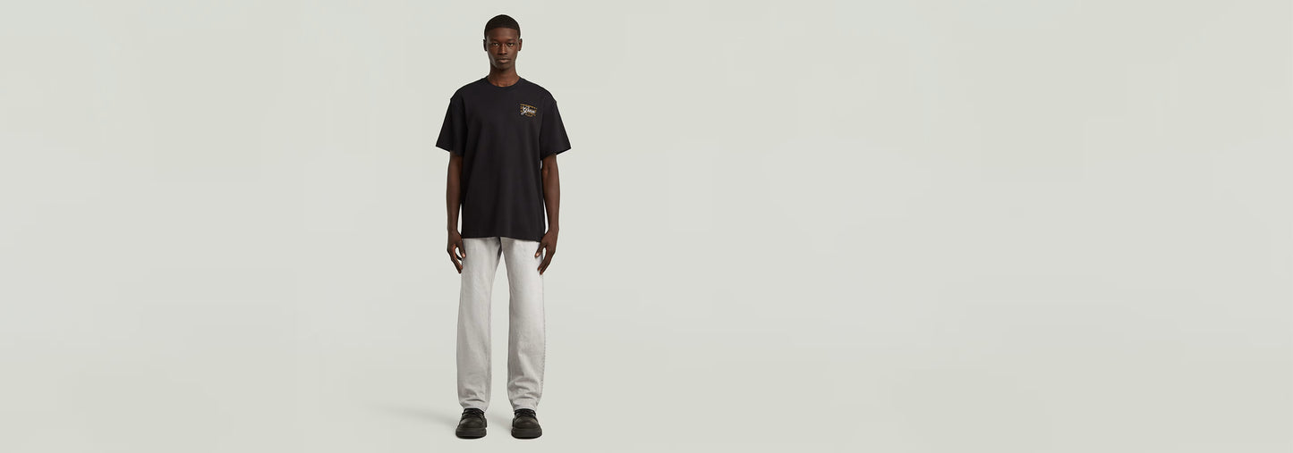 Modelo masculino vistiendo camiseta Script en color negro y pantalones blancos.