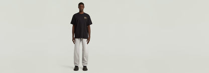 Modelo masculino vistiendo camiseta Script en color negro y pantalones blancos.