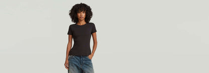 Mujer usando una camiseta Slim Rib negra con cuello redondo y jeans, mostrando un look versátil y atemporal.