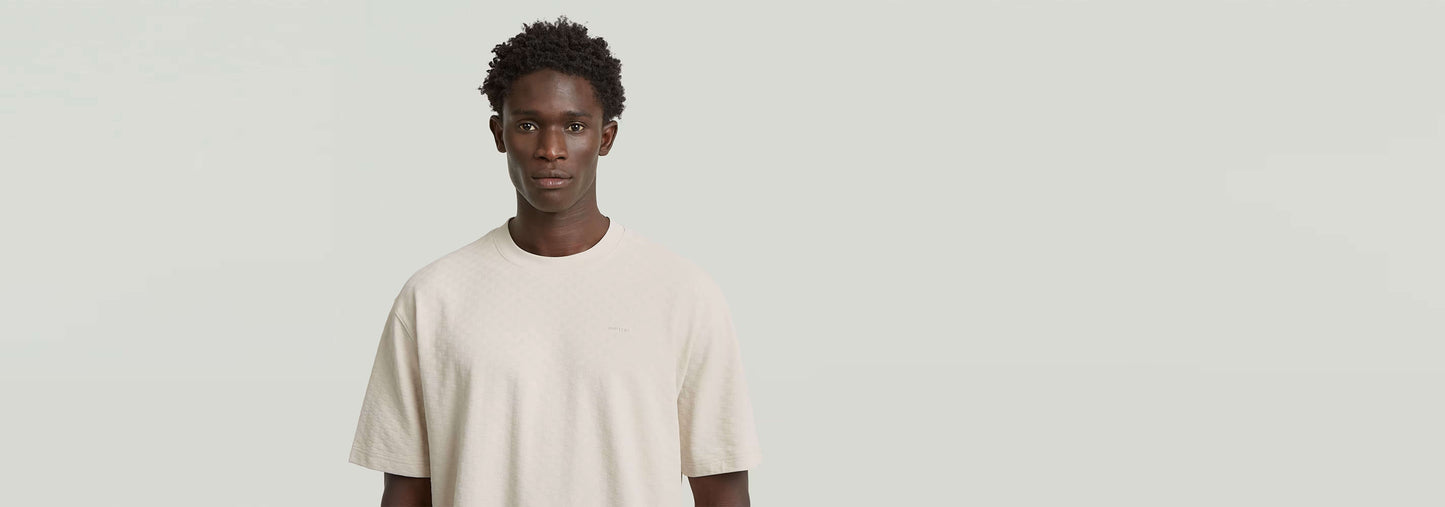 Modelo usando la Camiseta Structured Relaxed Base de color claro, muestra su corte relajado y diseño moderno.