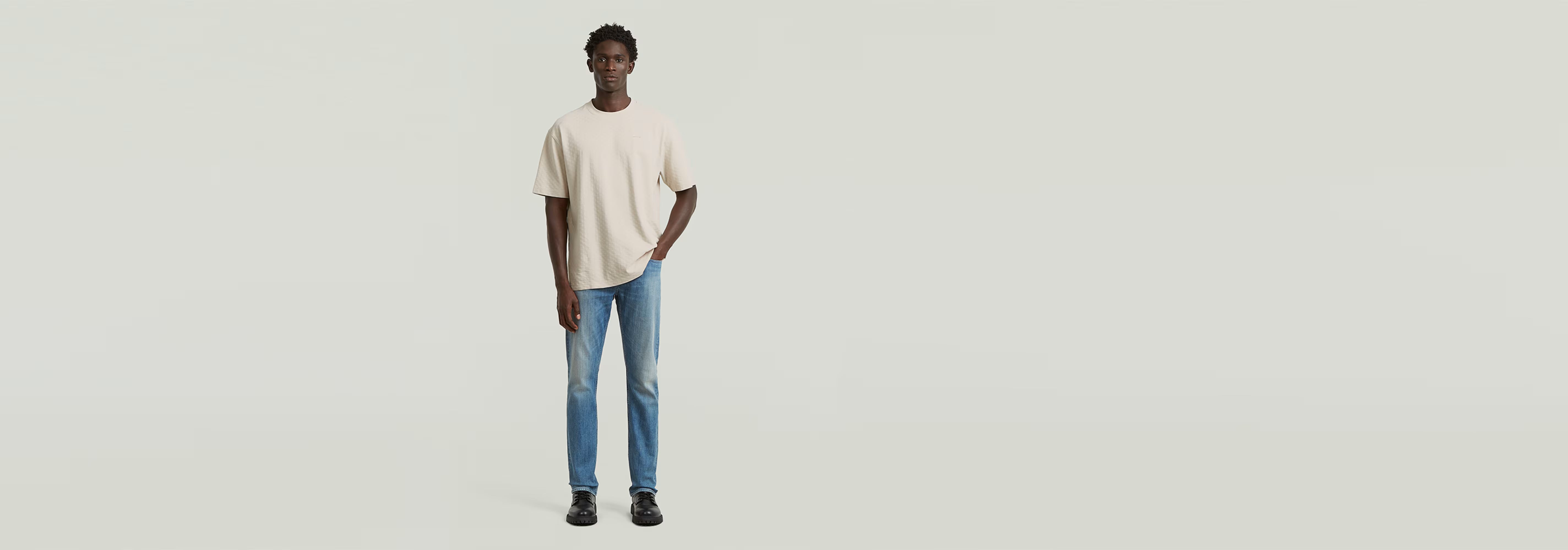 Hombre vistiendo una camiseta Structured Relaxed Base de corte relajado y jeans, mostrando un estilo moderno.