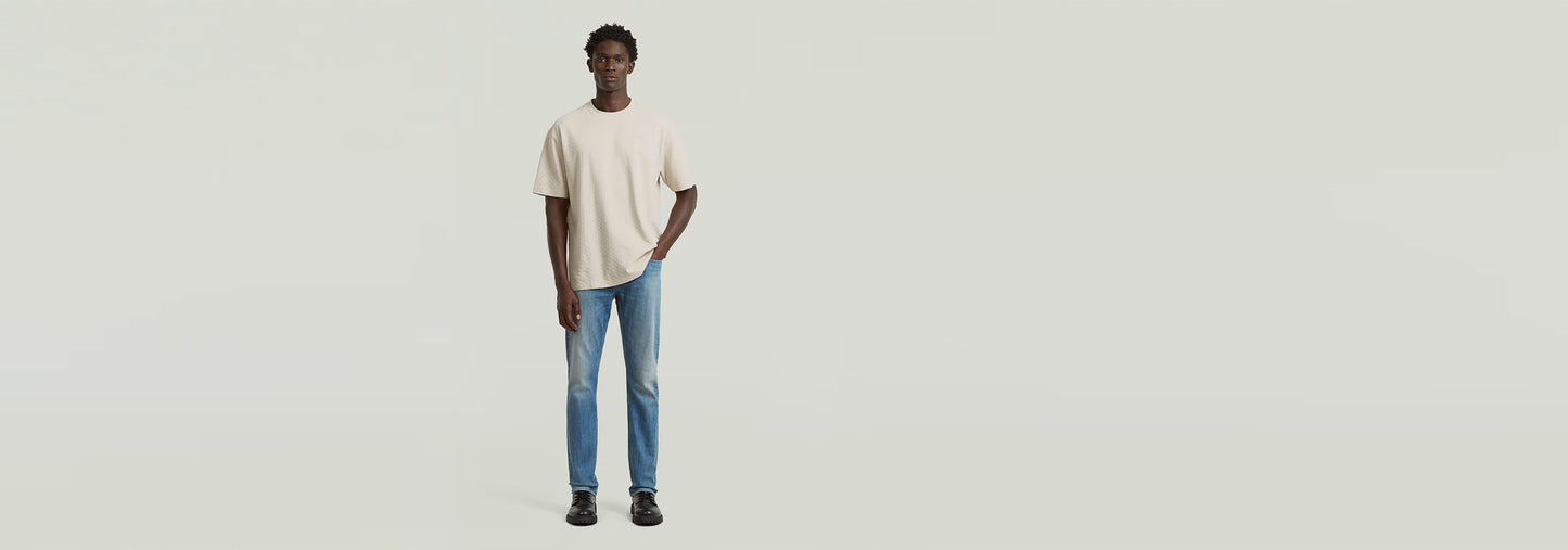 Hombre vistiendo una camiseta Structured Relaxed Base de corte relajado y jeans, mostrando un estilo moderno.