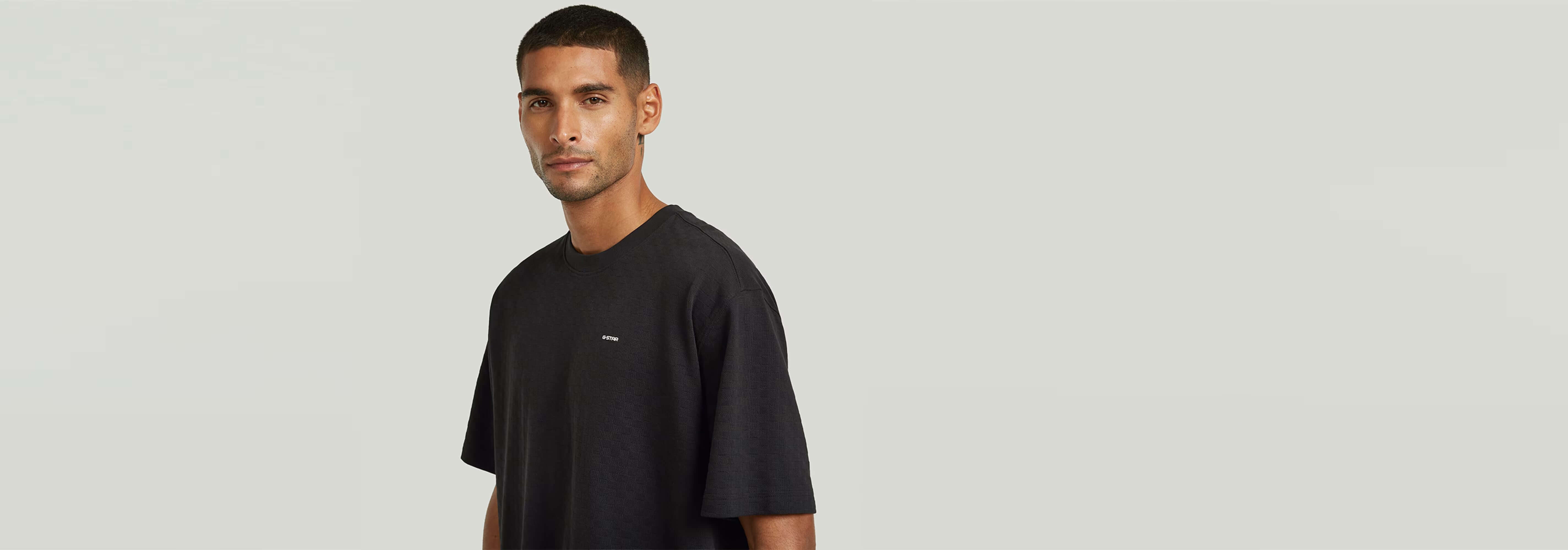 Hombre luciendo una camiseta negra, mostrando la Camiseta Structured Relaxed Base con corte relajado y cuello redondo.