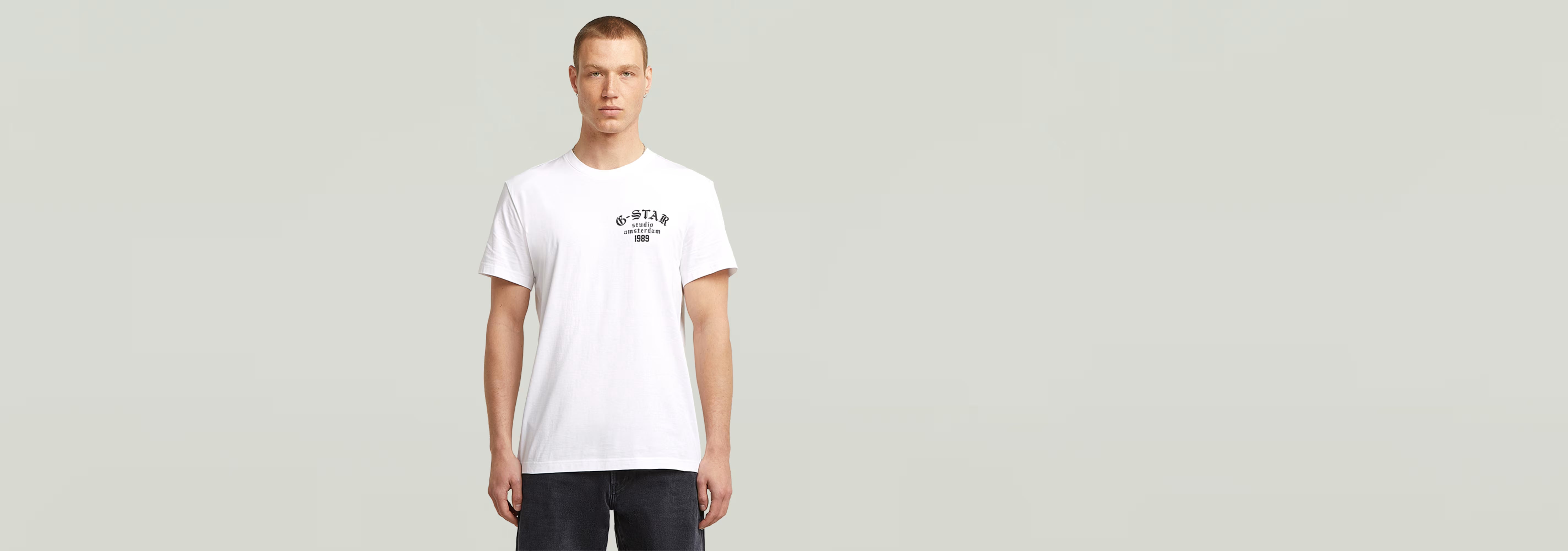 Modelo luciendo la Camiseta Studio AMS blanca con diseño gráfico en el pecho y cuello redondo.