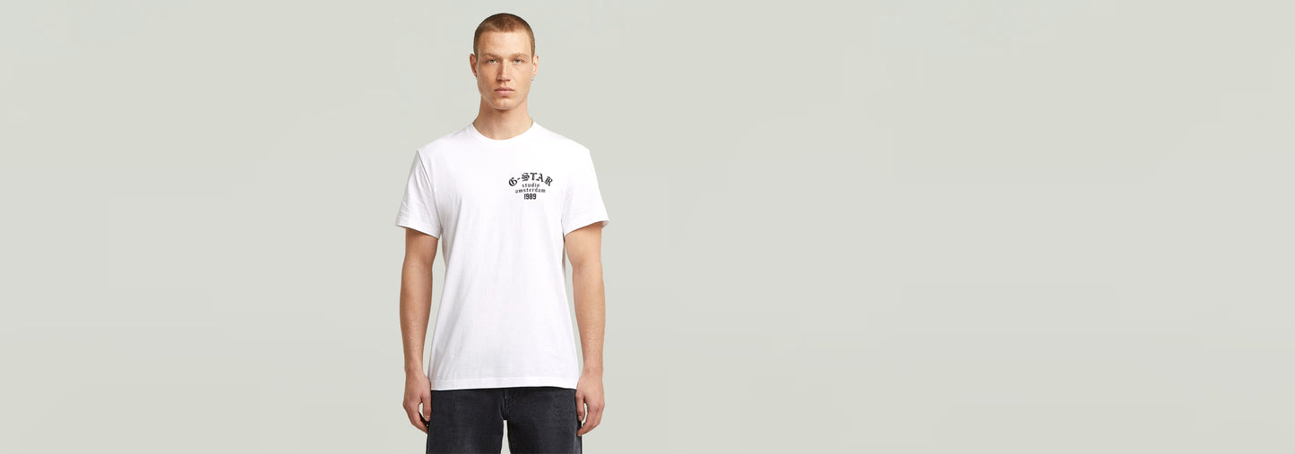 Modelo luciendo la Camiseta Studio AMS blanca con diseño gráfico en el pecho y cuello redondo.
