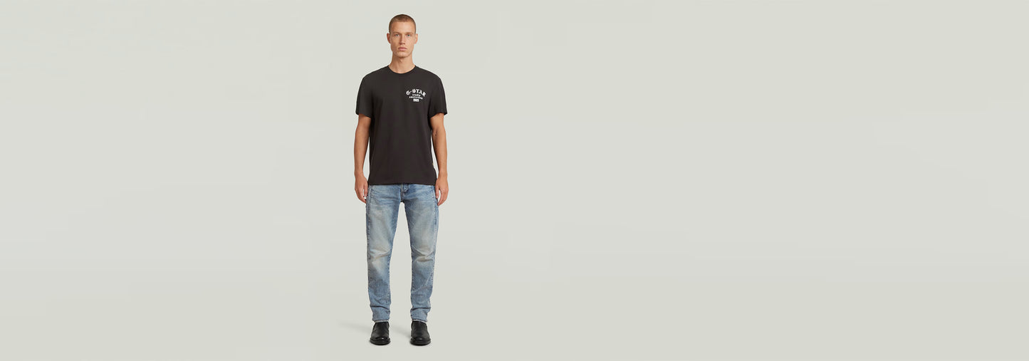 Modelo vistiendo la Camiseta Studio AMS negra con diseño gráfico, jeans claros y calzado negro.