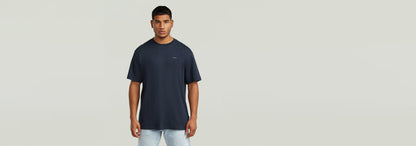 Modelo usando la Camiseta True Regular de cuello redondo en color oscuro, con ajuste cómodo y gráfico en la parte delantera.
