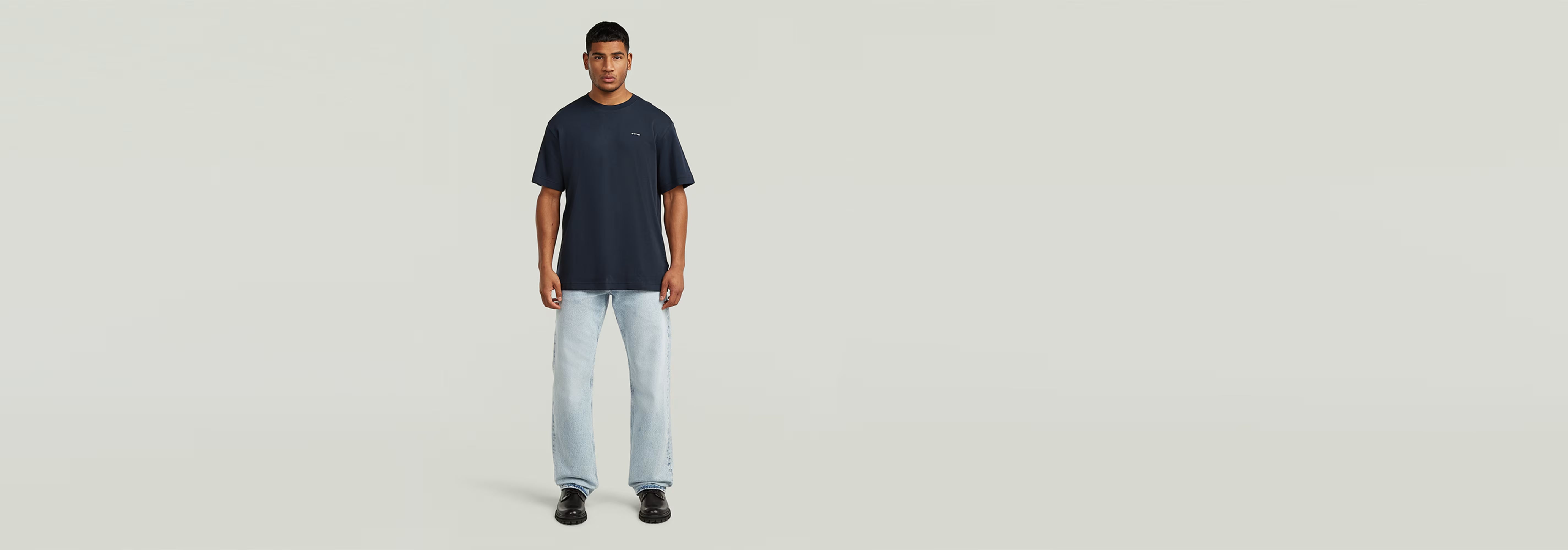 Modelo usando la Camiseta True Regular de color azul con jeans claros, fondo neutro y diseño simple.