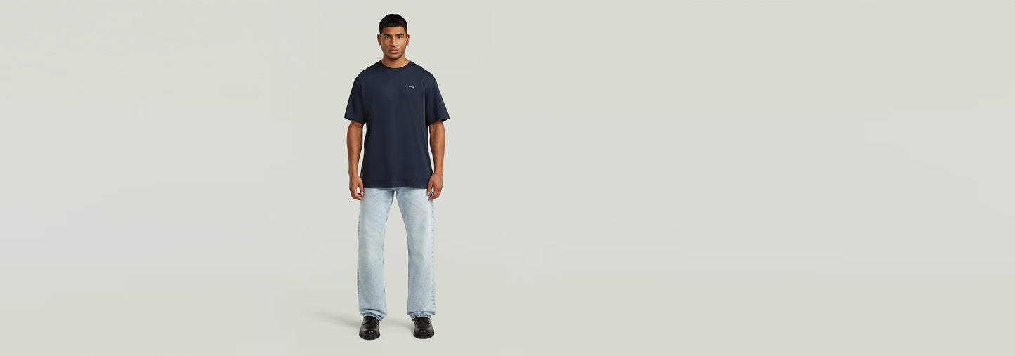 Modelo usando la Camiseta True Regular de color azul con jeans claros, fondo neutro y diseño simple.