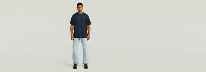 Modelo usando la Camiseta True Regular de color azul con jeans claros, fondo neutro y diseño simple.