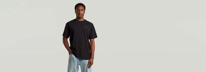 Modelo luciendo la camiseta True Regular de cuello redondo en color negro, con jeans y fondo neutral.