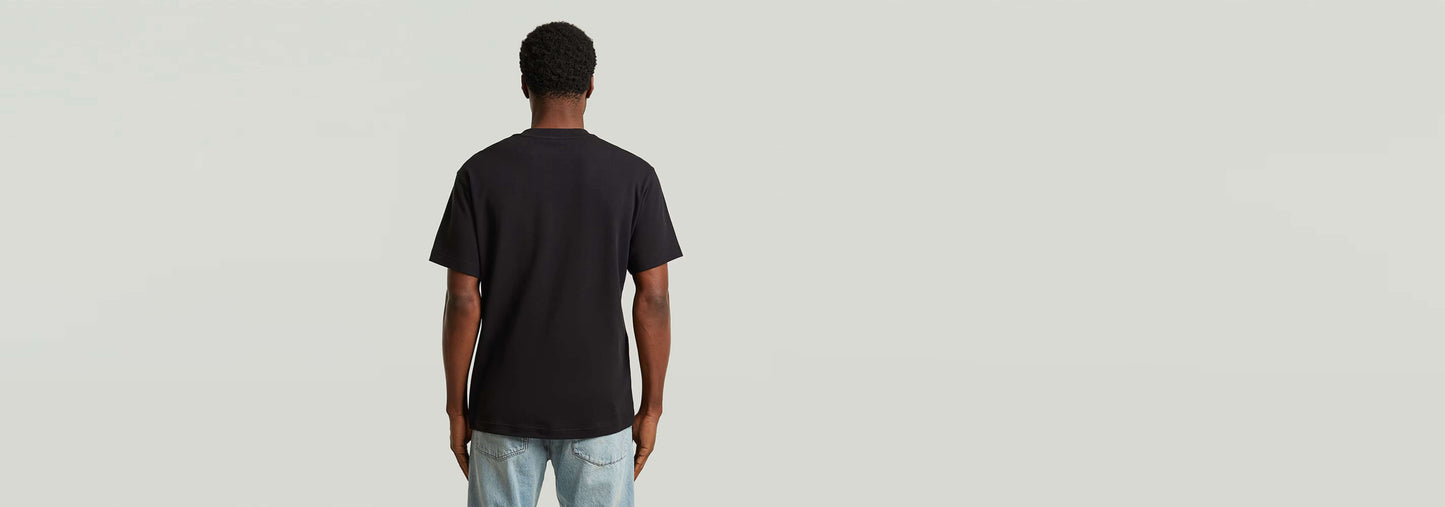 Hombre de espaldas vistiendo la Camiseta True Regular negra, mostrando su diseño clásico y ajuste cómodo.
