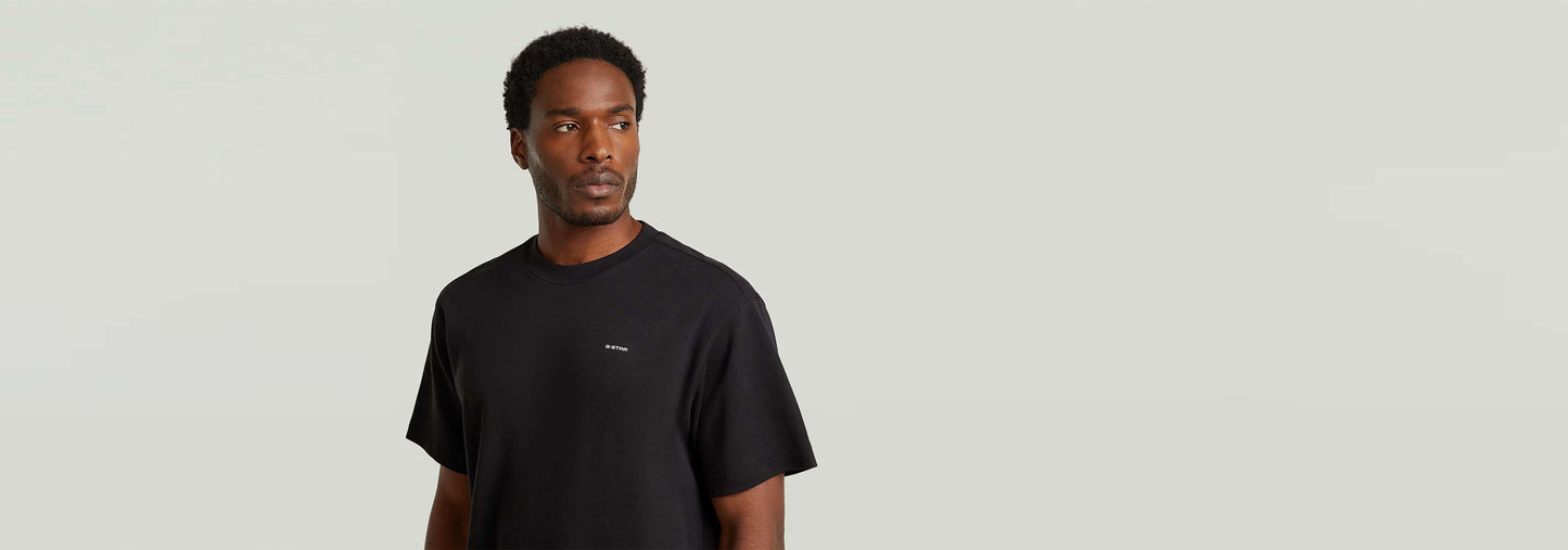 Hombre usando una camiseta True Regular de color negro con cuello redondo y manga corta.