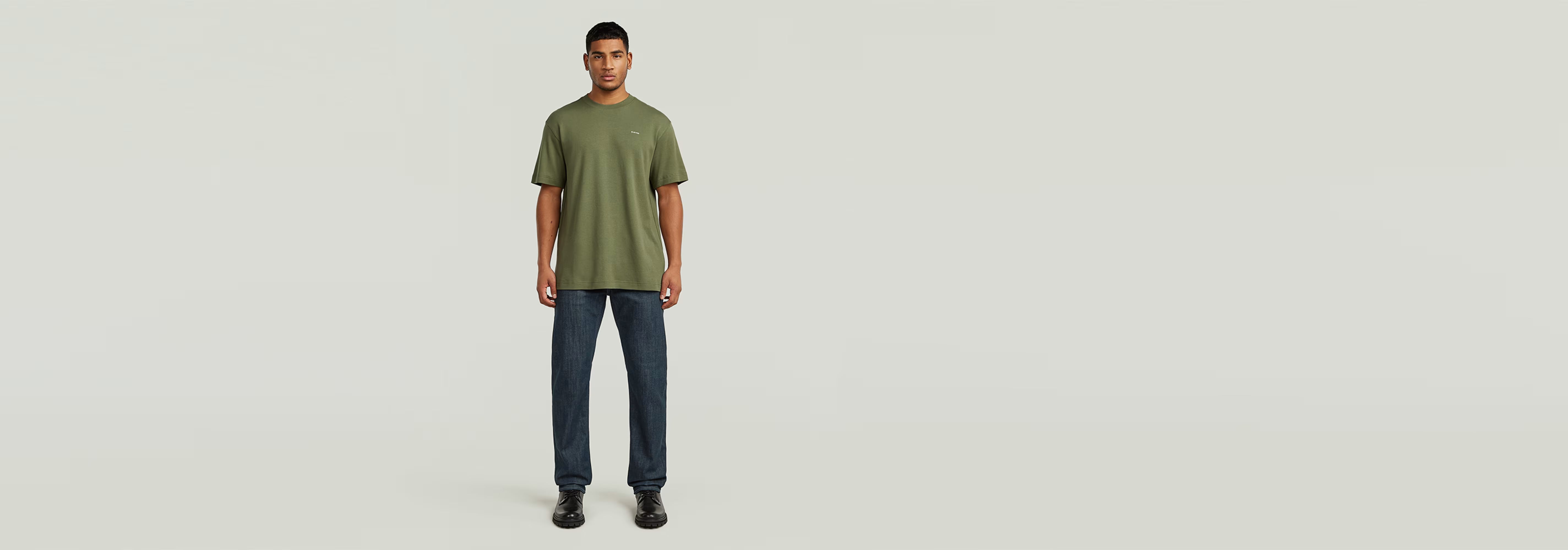 Hombre luciendo la Camiseta True Regular de cuello redondo en color verde, combinado con pantalones oscuros.