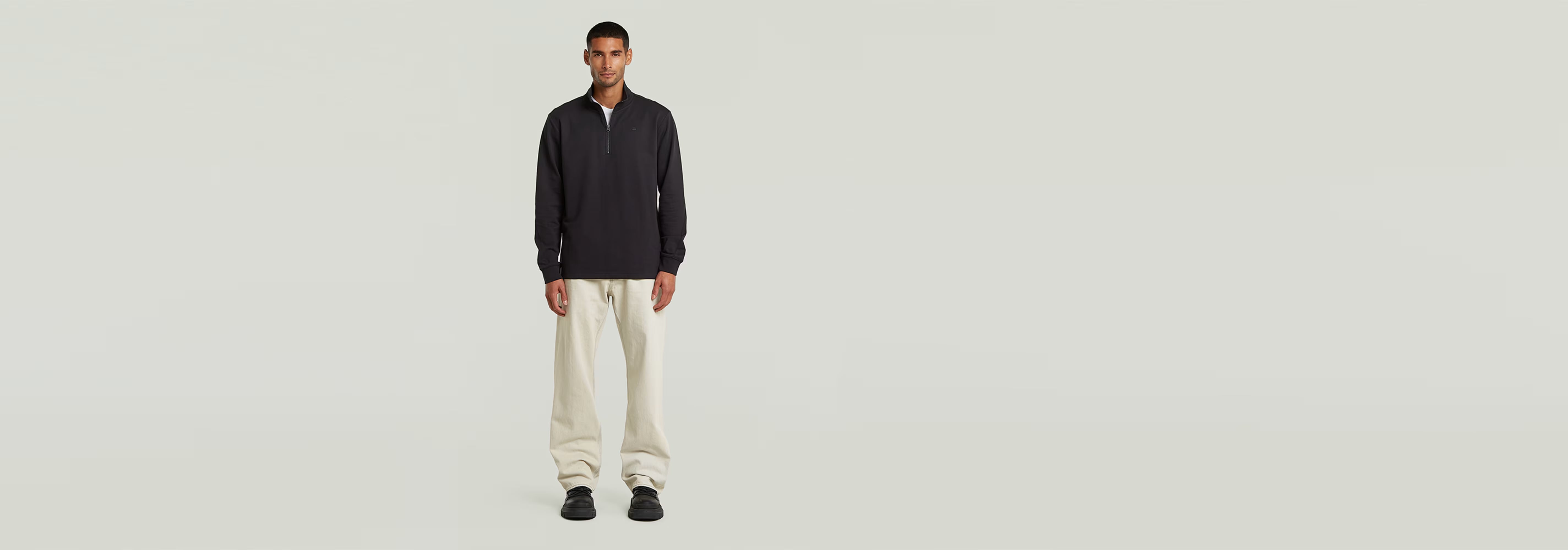 Camiseta Tweeter Half Zip Long Sleeve modelo masculino con pantalones claros, fondo neutro.