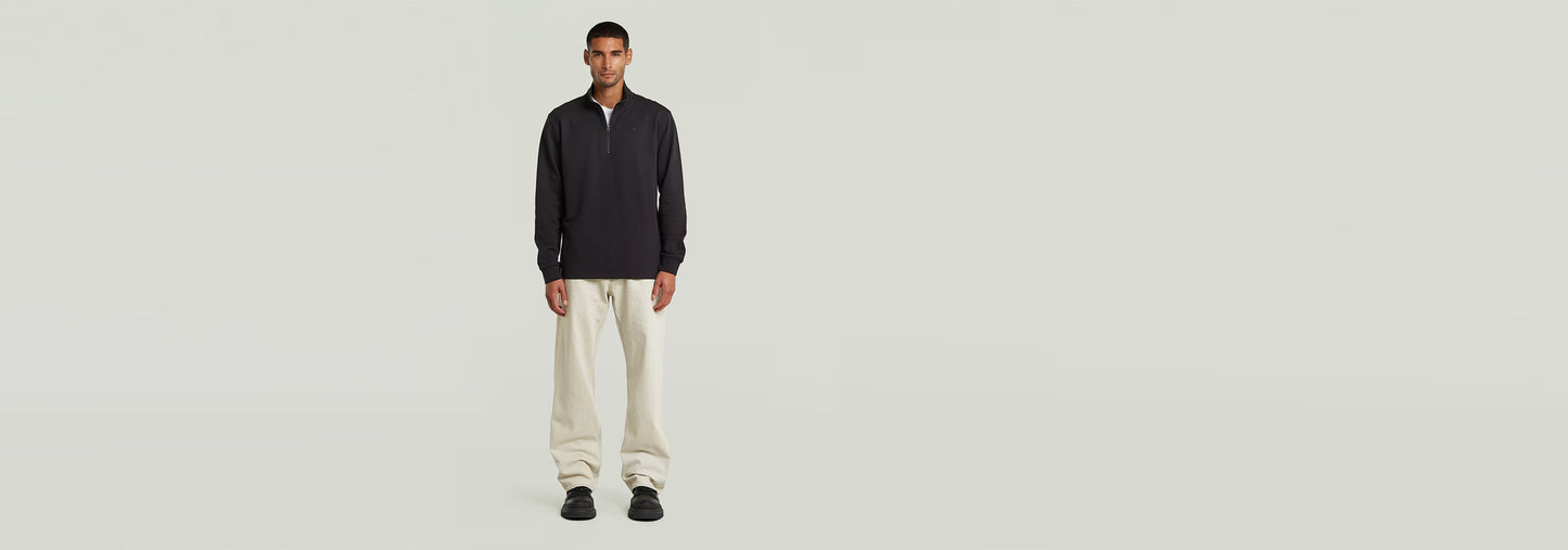 Camiseta Tweeter Half Zip Long Sleeve modelo masculino con pantalones claros, fondo neutro.