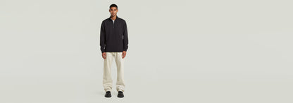 Camiseta Tweeter Half Zip Long Sleeve modelo masculino con pantalones claros, fondo neutro.
