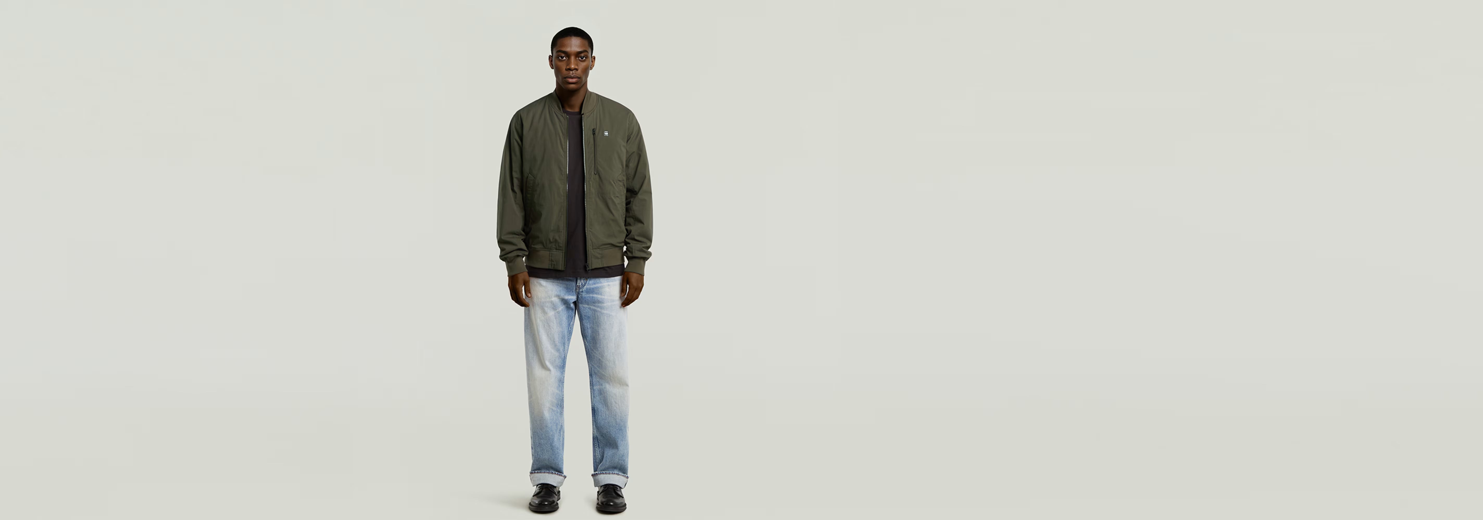 Hombre usando una Cazadora de aviador Tech de diseño acolchado con jeans claros.