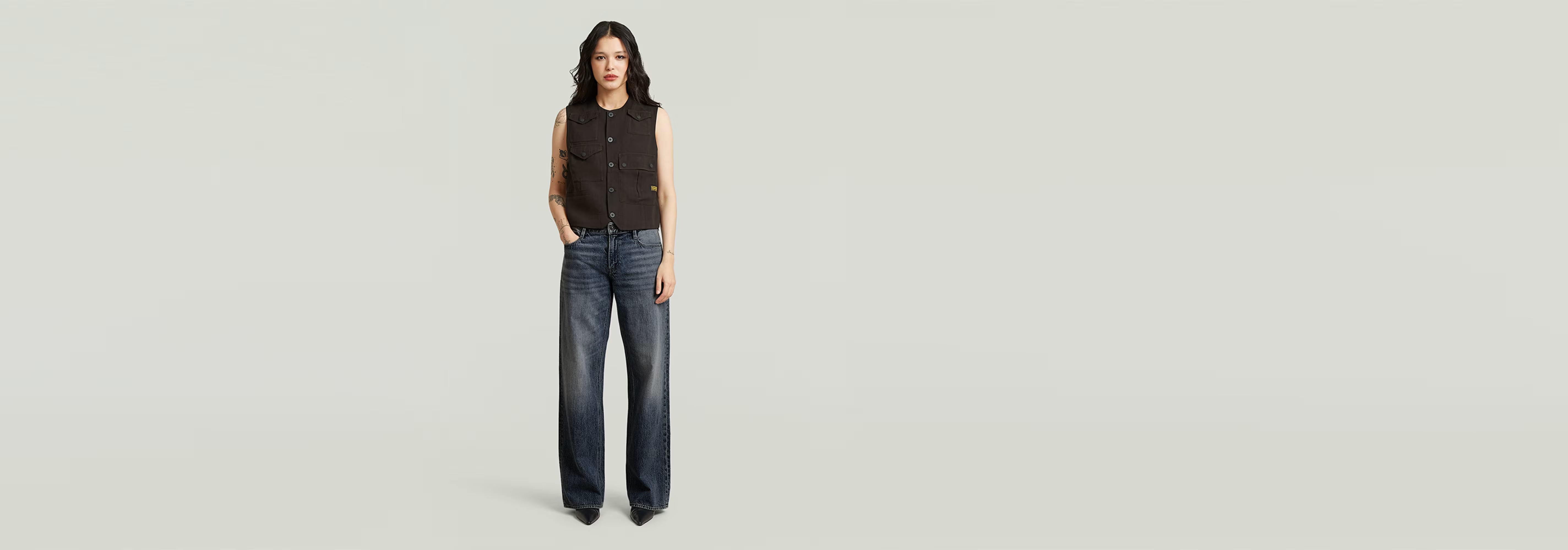 Mujer luciendo chaleco Pocket de botones con pantalones de denim anchos.
