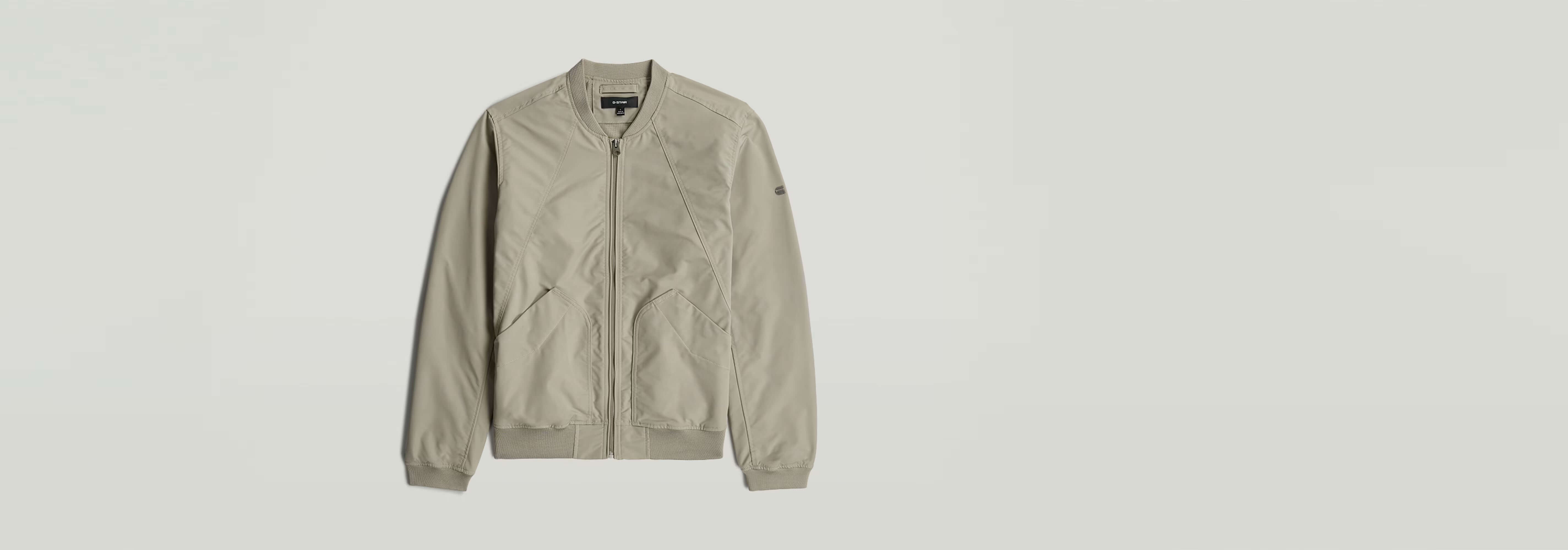 Chaqueta Bomber Unpadded en color beige, con bolsillos y cierre de cremallera, sin acolchado.