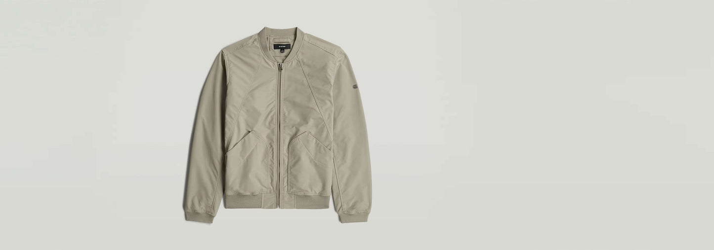 Chaqueta Bomber Unpadded en color beige, con bolsillos y cierre de cremallera, sin acolchado.