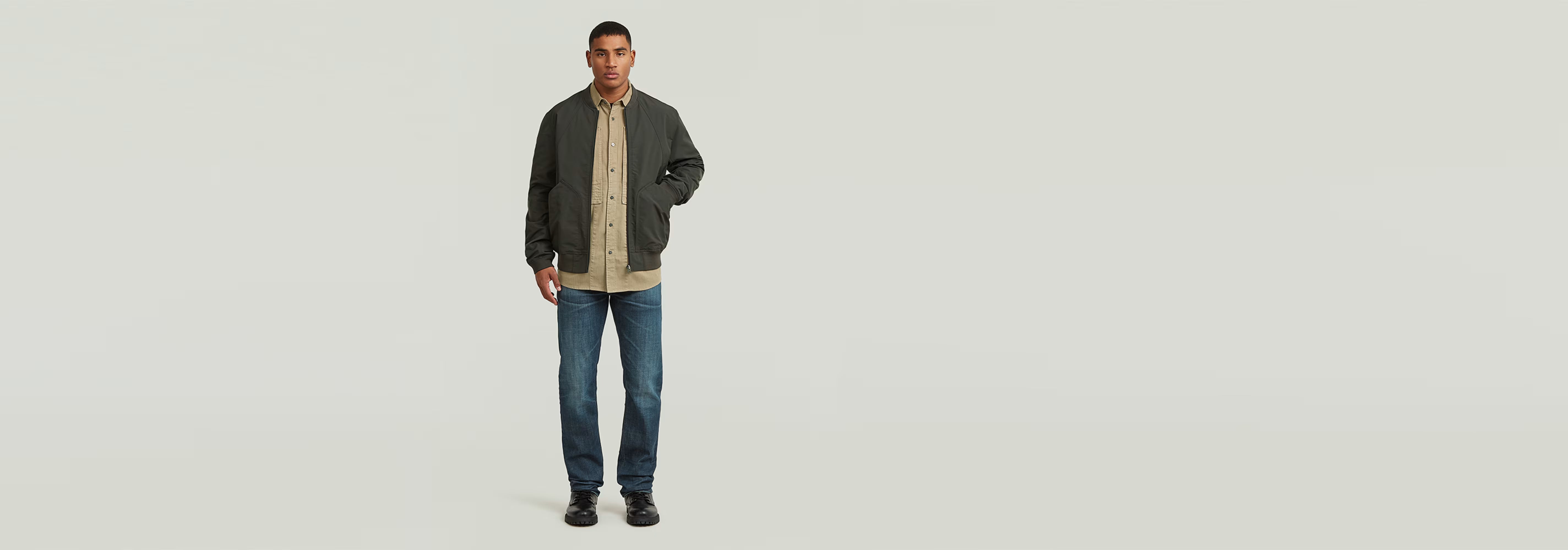 Hombre usando chaqueta Bomber Unpadded en ambiente minimalista, con jeans y camiseta, estilo moderno.