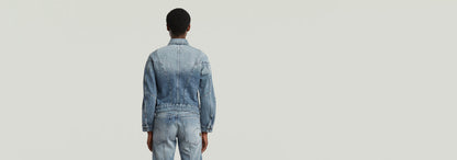 Modelo vistiendo una chaqueta Kitoh 3D de denim, vista trasera en fondo neutro.