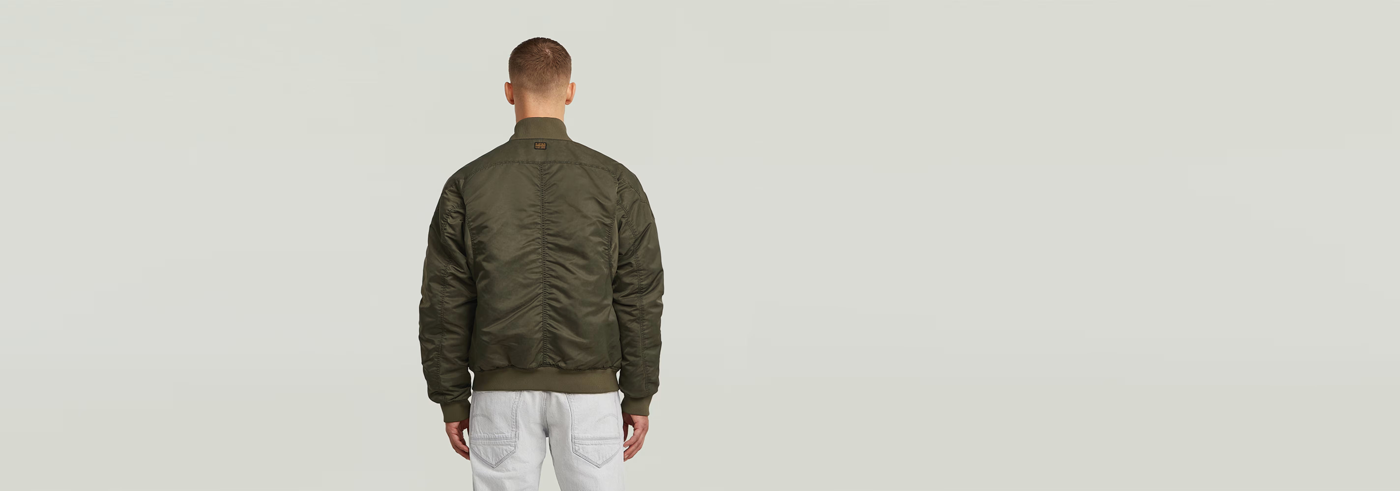 Hombre de espaldas usando la chaqueta GA-1 Lightweight Padded Bomber en color verde.