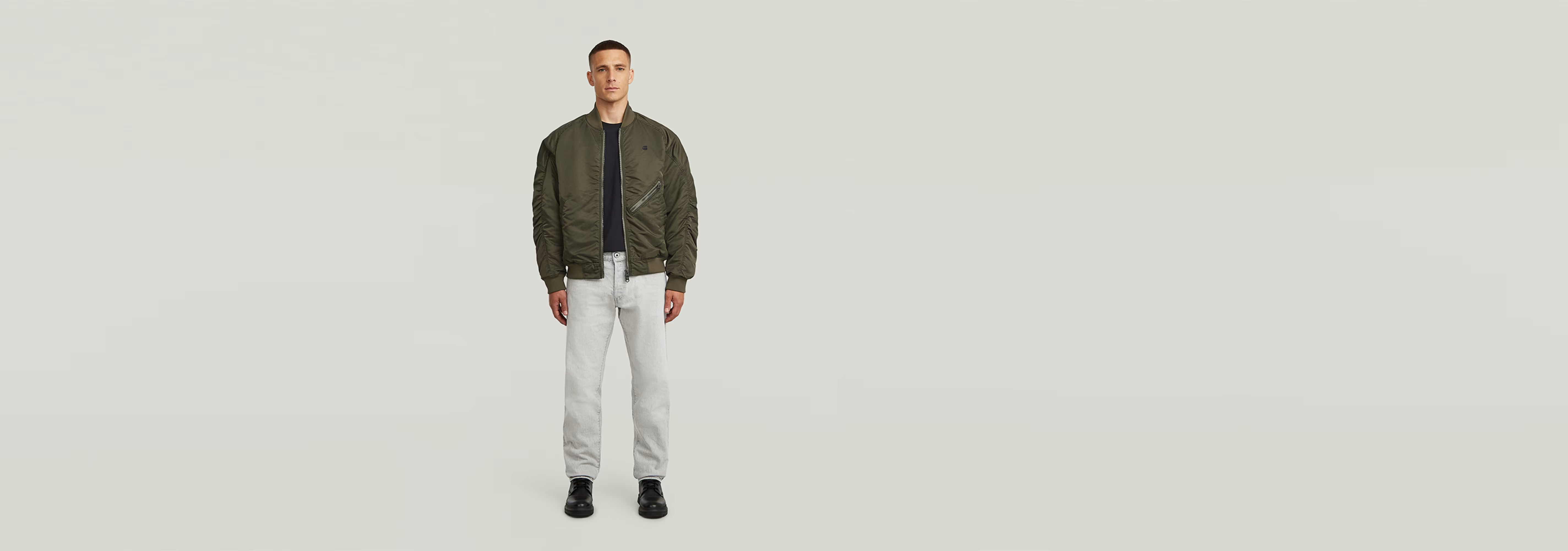 Modelo usando la chaqueta GA-1 Lightweight Padded Bomber con pantalones claros y fondo neutro.