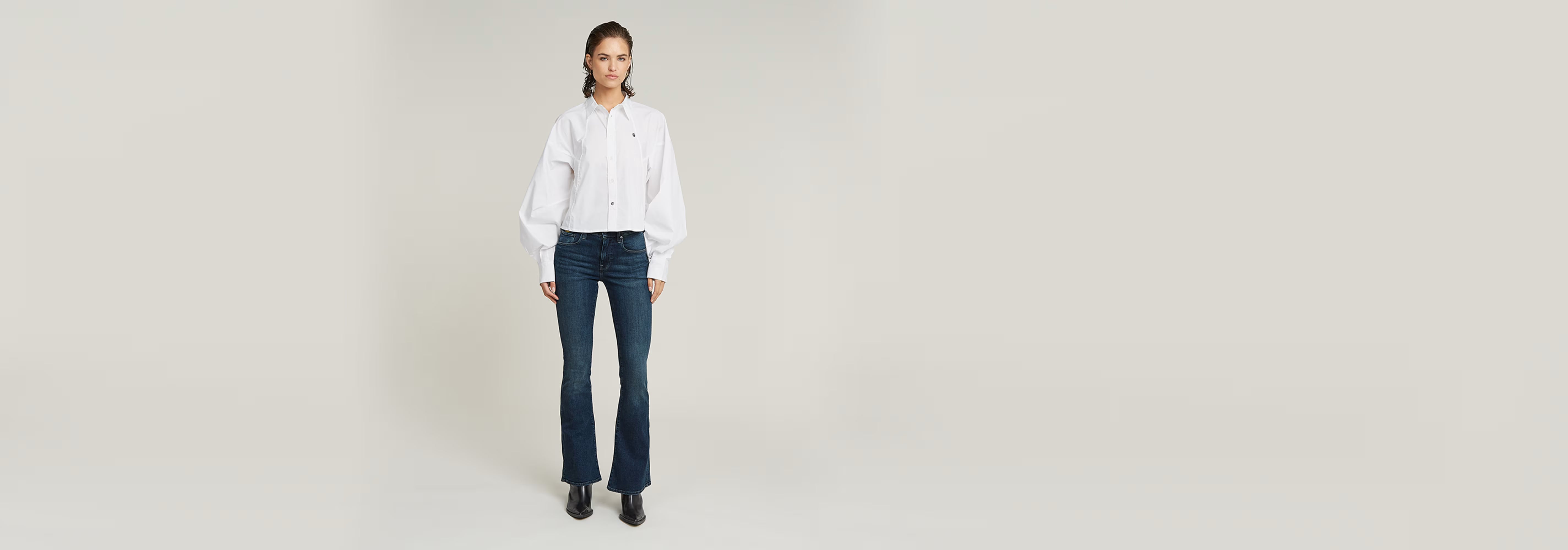 Mujer vistiendo Jeans 3301 Flare en color azul con blusa blanca, pose de pie.