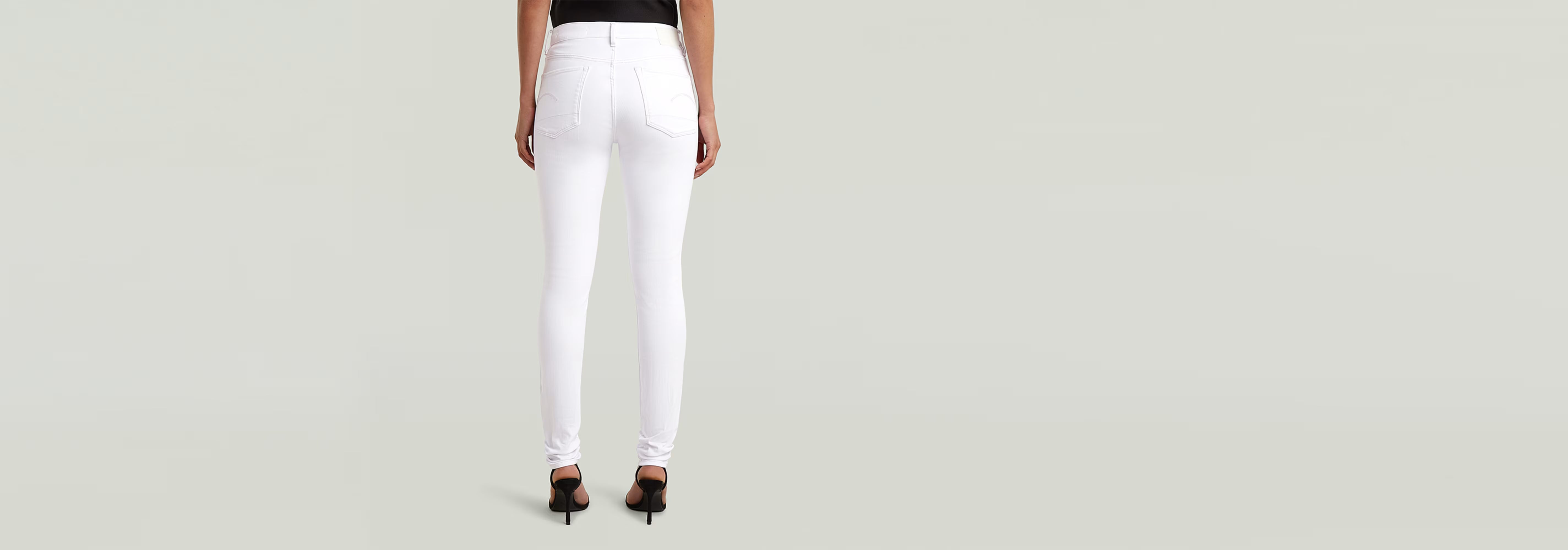 Mujer de espaldas vistiendo Jeans 3301 Skinny blancos con estilo clásico y construcción de cinco bolsillos.