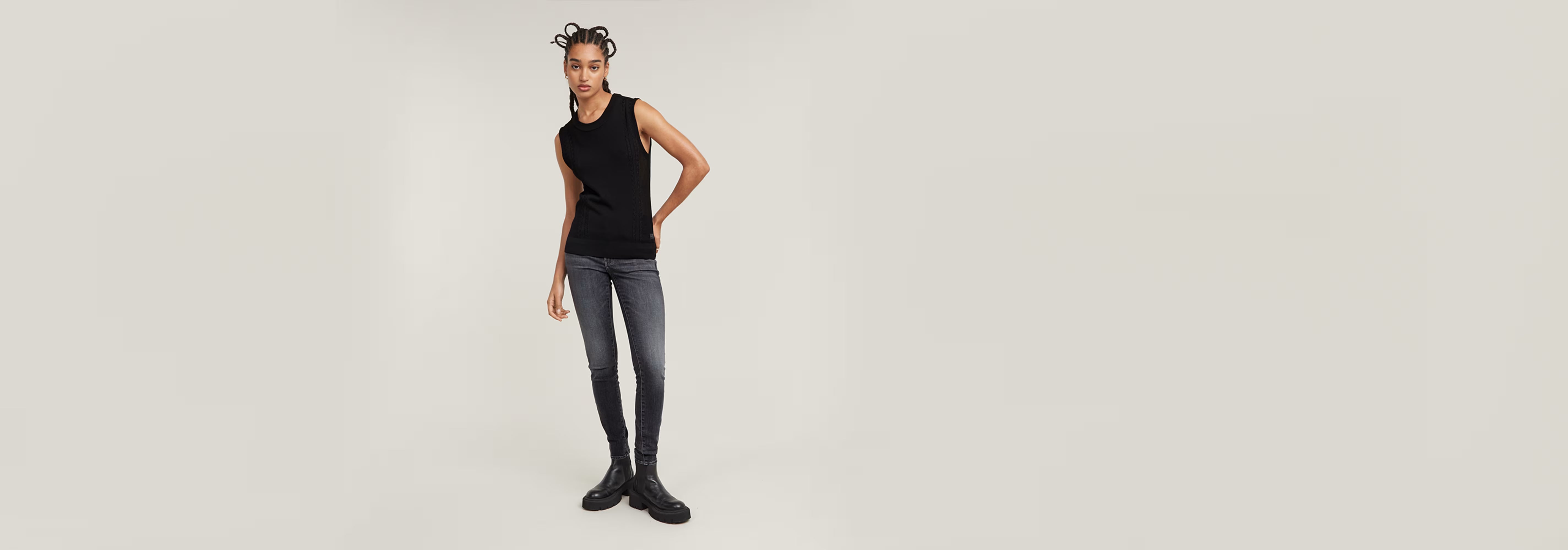 Mujer usando Jeans 3301 Skinny en un fondo claro, combinando con una camiseta sin mangas negra.
