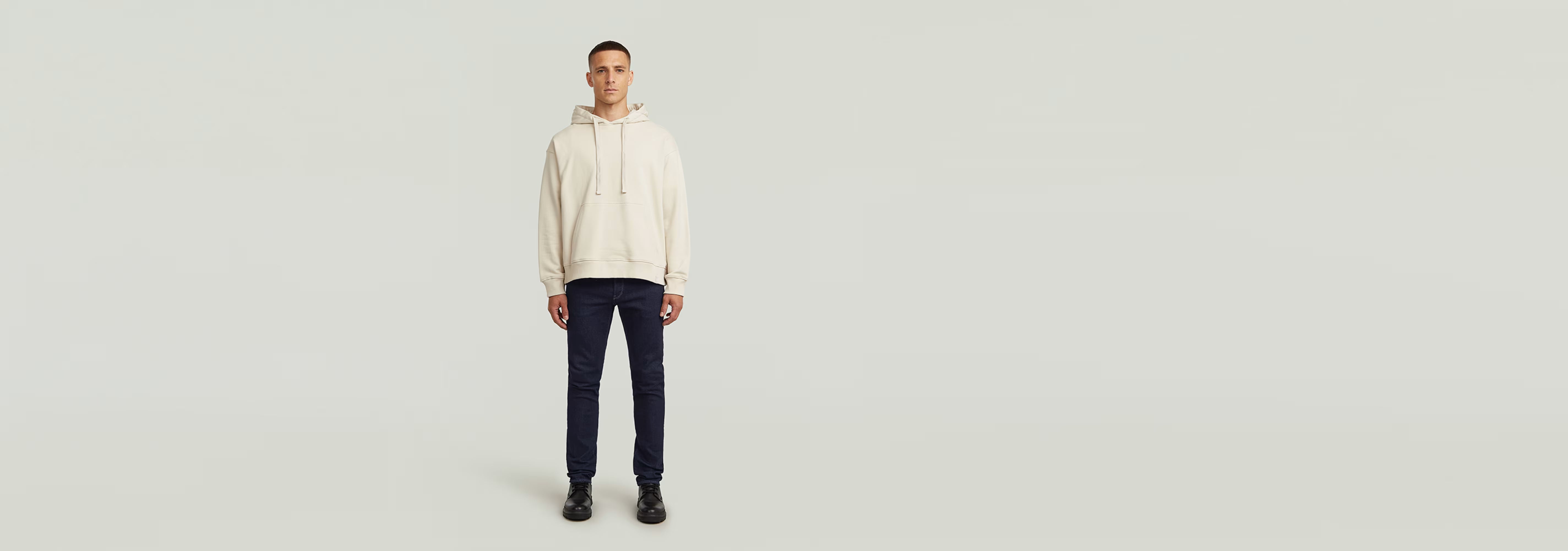 Modelo vistiendo Jeans 3301 Slim con sudadera beige, fondo claro y minimalista.