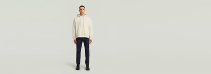 Modelo vistiendo Jeans 3301 Slim con sudadera beige, fondo claro y minimalista.