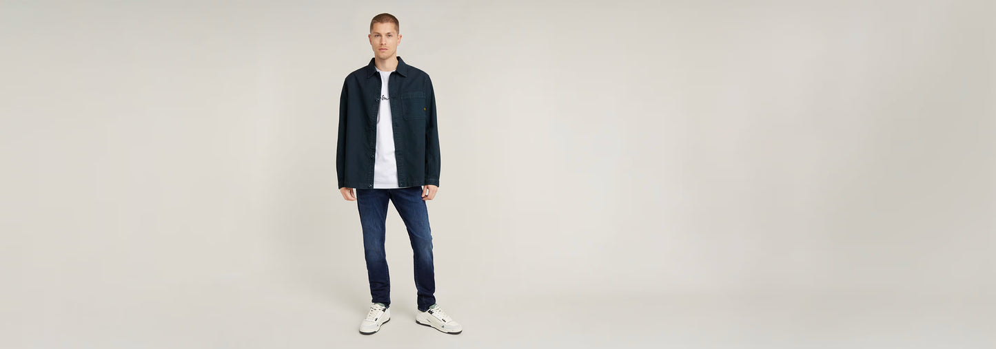 Modelo usando Jeans 3301 Slim con camiseta y chaqueta, fondo neutro.