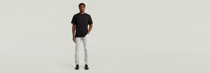 Hombre luciendo Jeans 3301 Slim, con corte ajustado y diseño clásico, camiseta negra y fondo minimalista.