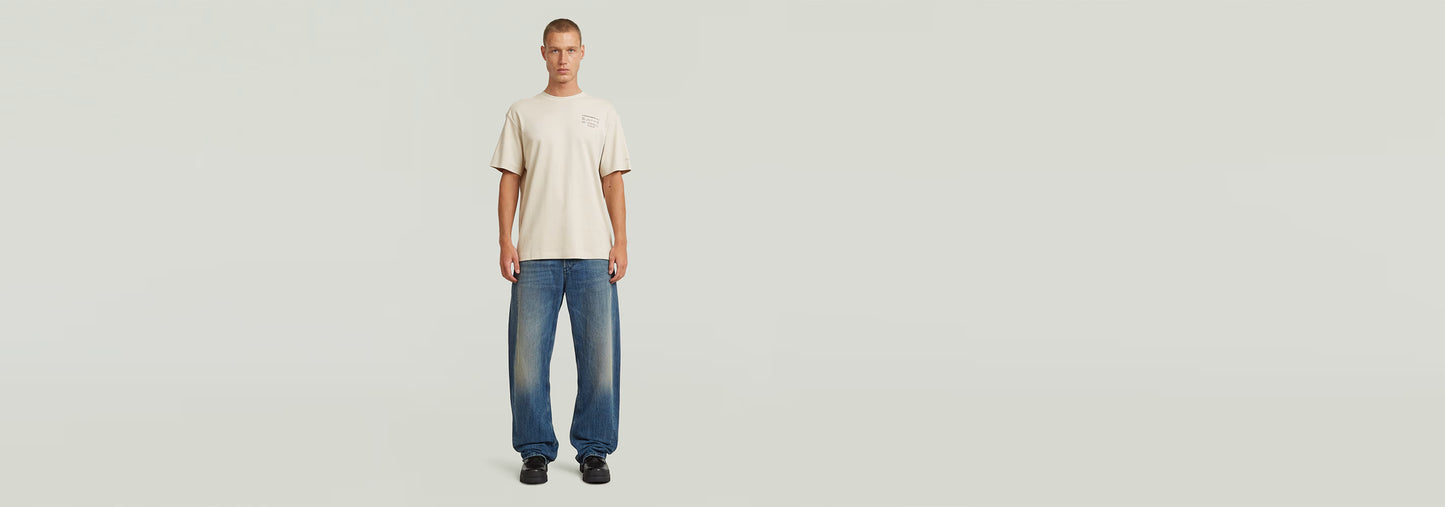 Modelo usando Jeans Bend Loose y camiseta beige en fondo claro, resaltando el estilo moderno de la colección Anatomic Denim.