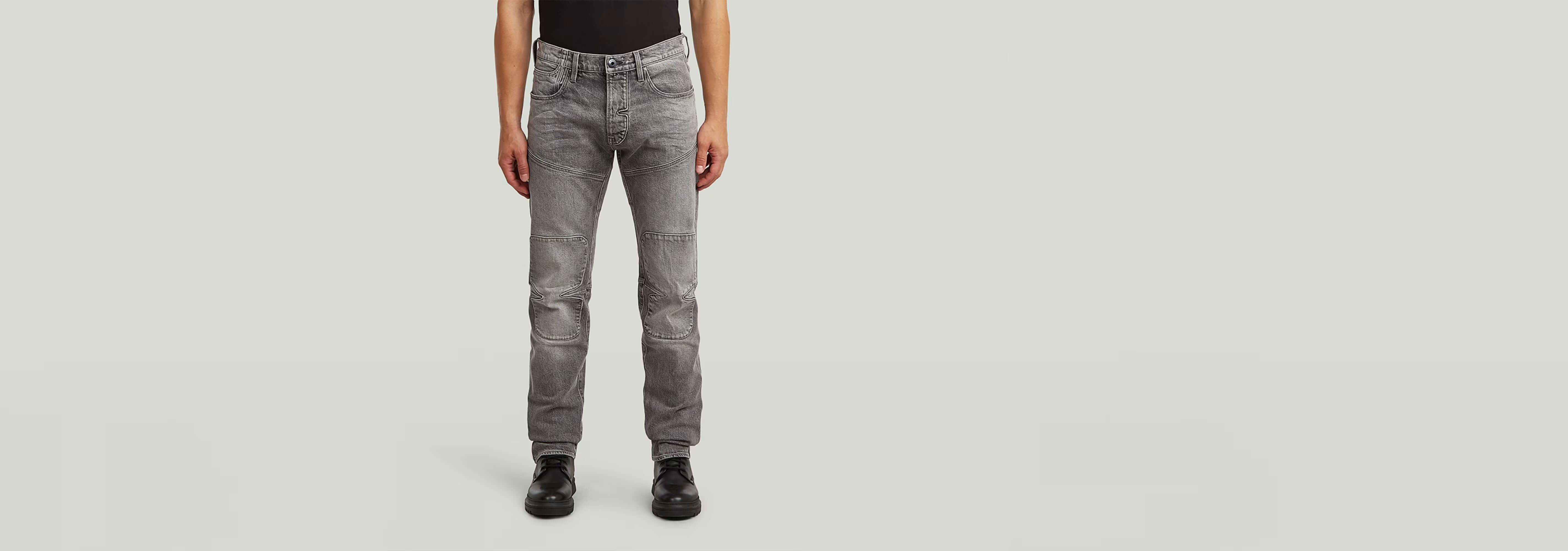 Jeans Biker Patched Slim en un hombre de pie, mostrando su diseño moderno y corte ajustado.