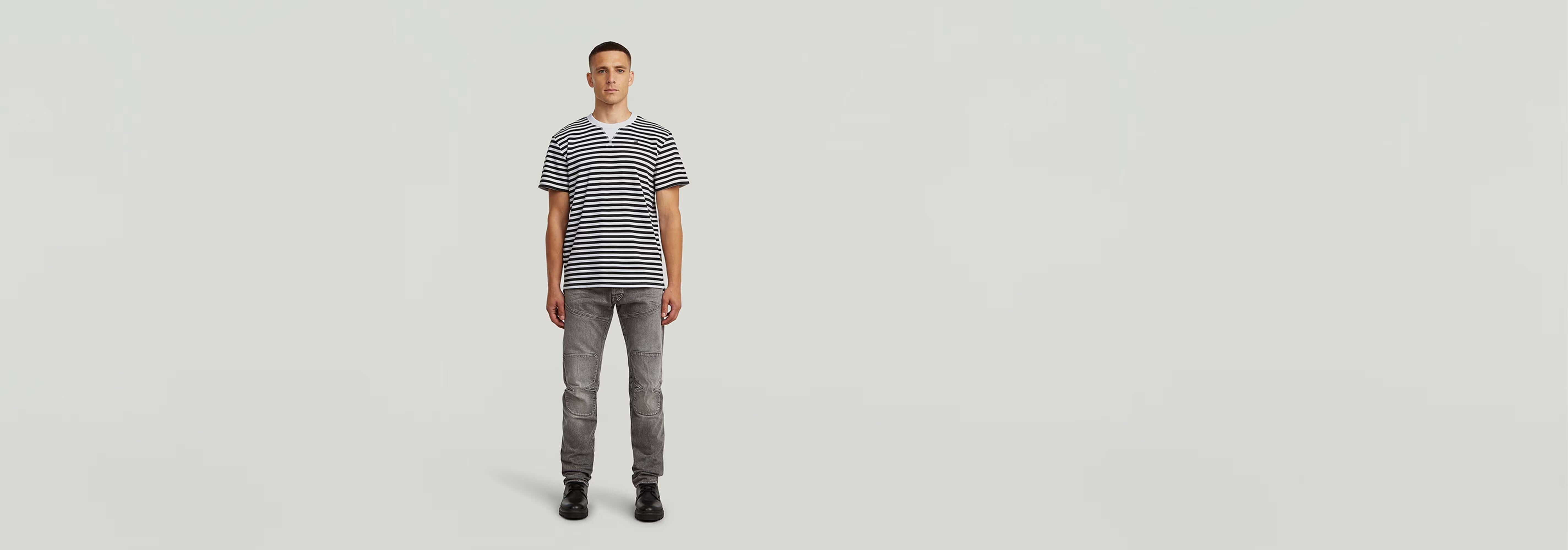 Modelo luciendo Jeans Biker Patched Slim con camiseta de rayas en fondo neutro.
