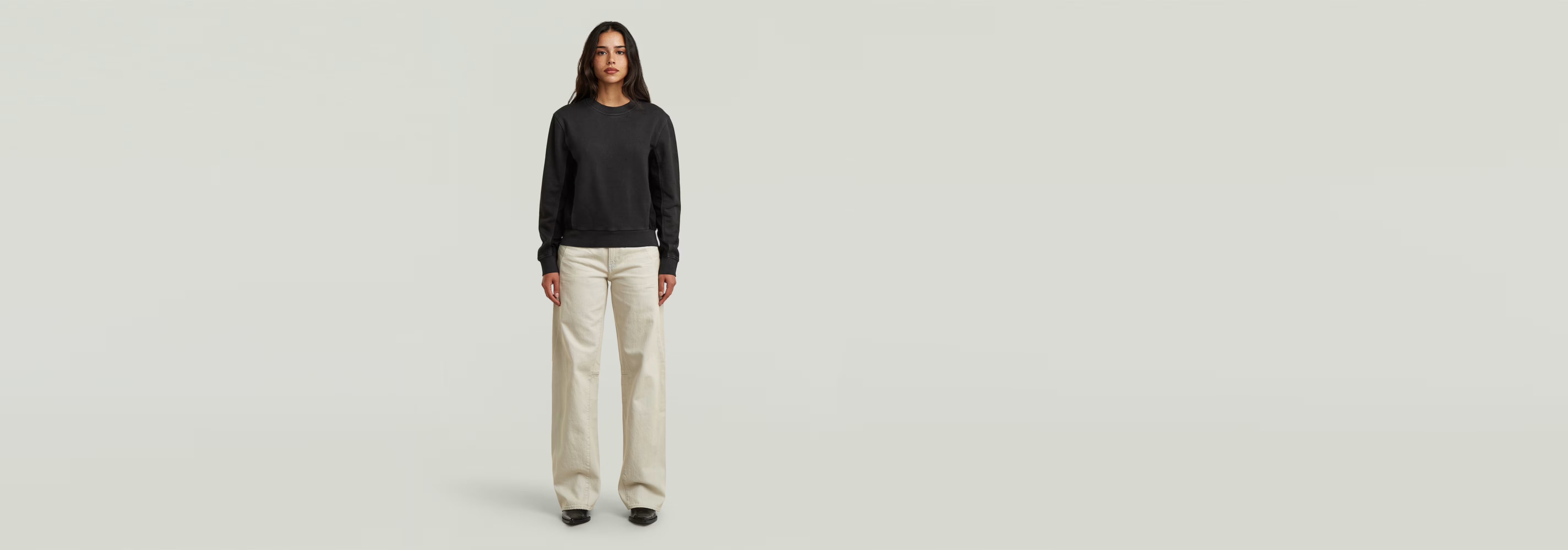 Mujer luciendo jeans Contor Barrel Loose de corte holgado con camiseta negra en fondo neutral.