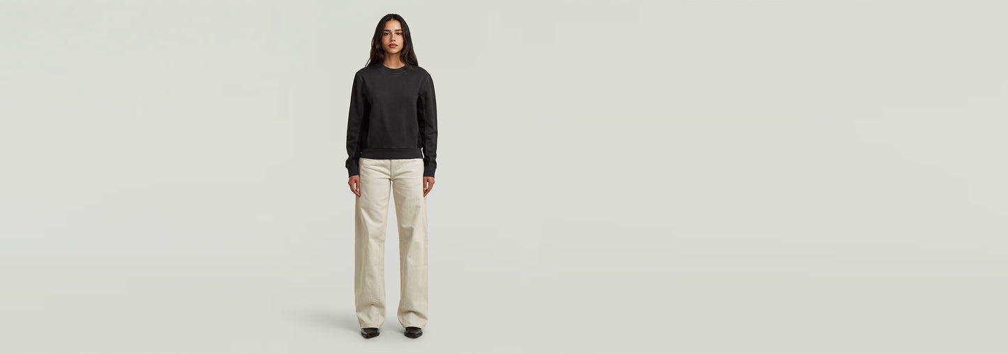 Mujer luciendo jeans Contor Barrel Loose de corte holgado con camiseta negra en fondo neutral.