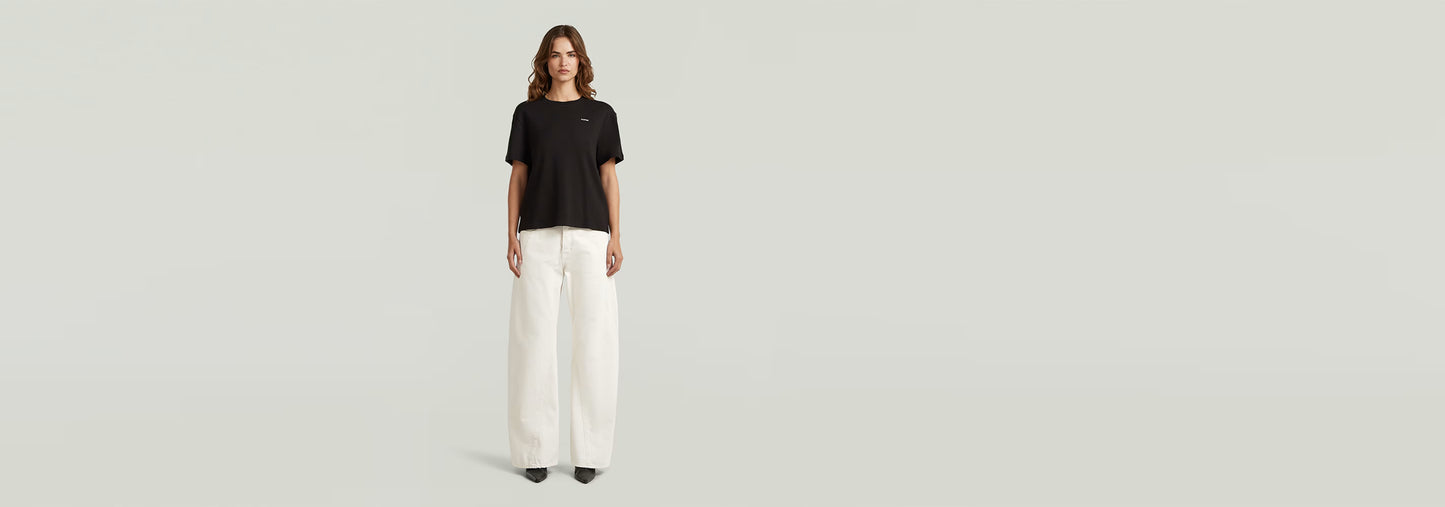 Modelo usando jeans Contor Barrel Wide con camiseta negra y pantalones anchos blancos.