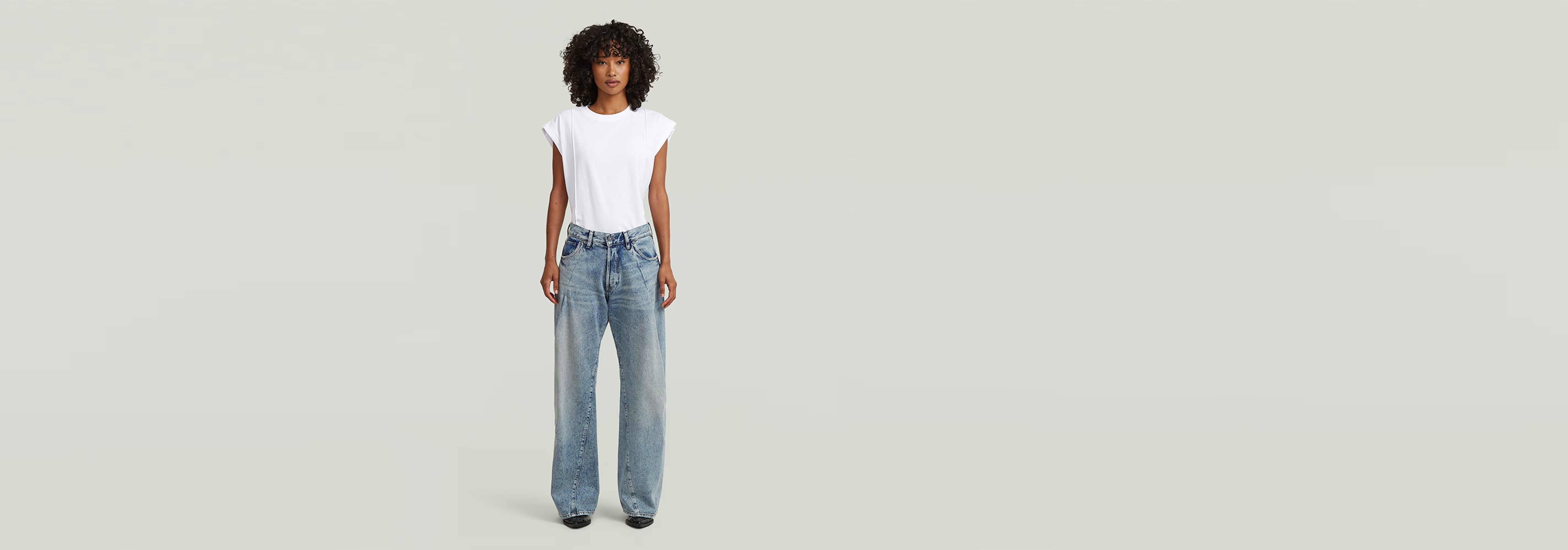 Mujer con camiseta blanca y jeans Contor Barrel Wide Pleat de corte holgado y talle bajo.