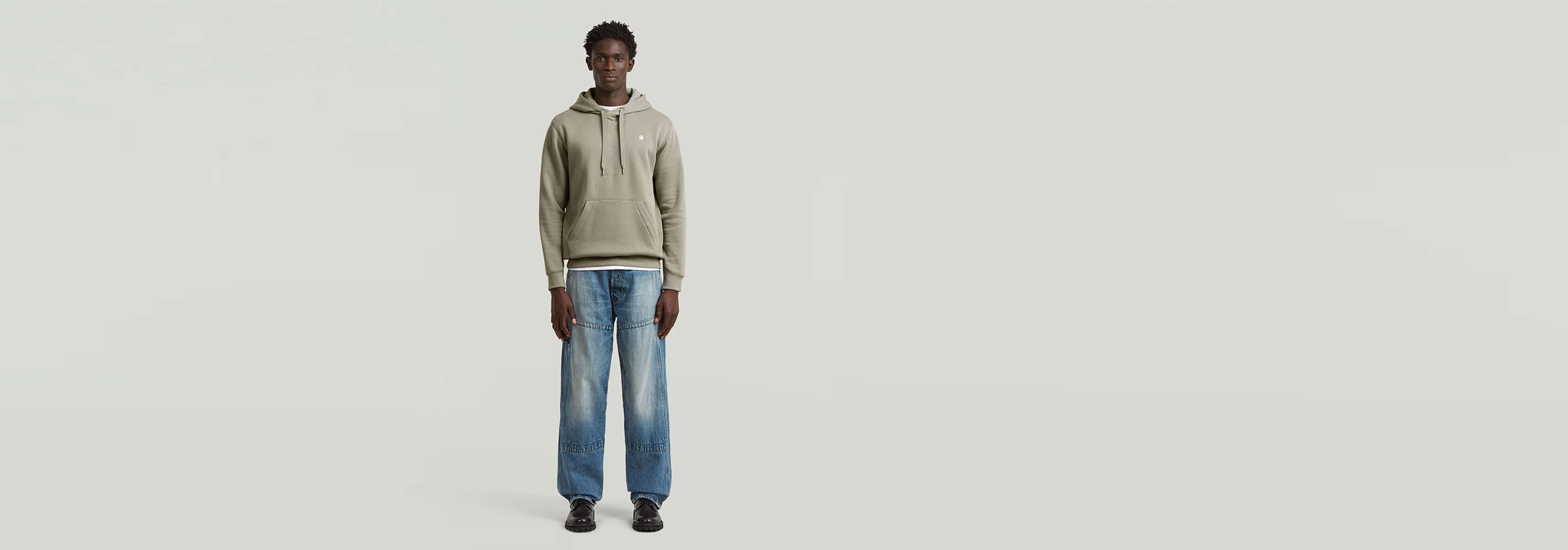 Hombre modelando los Jeans Contor Loose Carpenter con sudadera gris y zapatos negros.