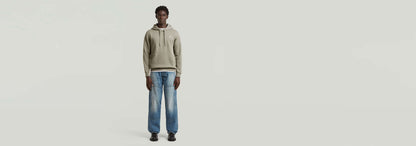 Hombre modelando los Jeans Contor Loose Carpenter con sudadera gris y zapatos negros.